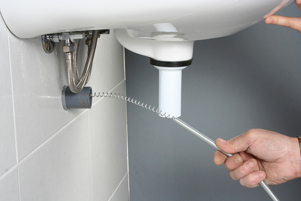 Prince Plumbing - image of plumber using snake line to clear a drain pipe