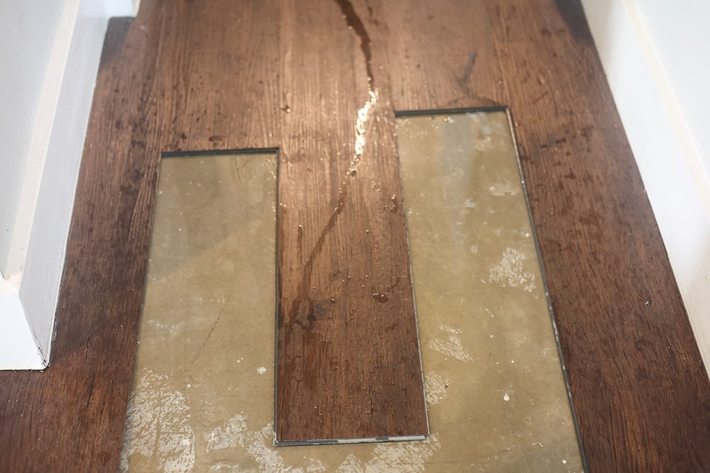 Image of a wet floor with wood flooring partially removed due to a slab leak